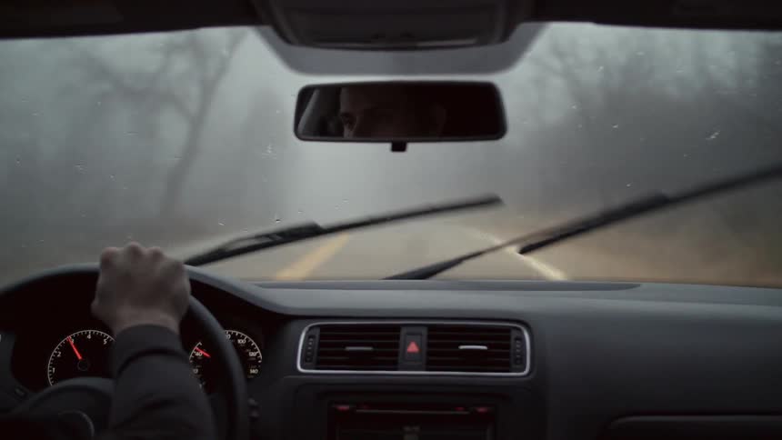 A person is driving in the fog