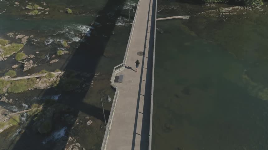 A person jogging on a bridge over a river