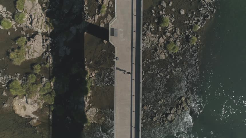 A person is walking on a bridge by the coast line