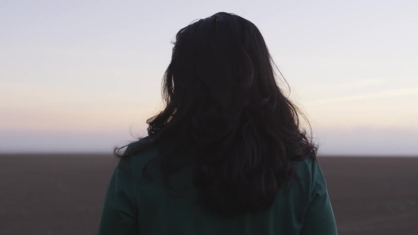 A woman facing away from the camera and walking