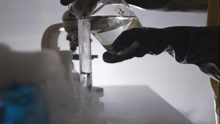 A person pours a clear solution in to a test tube