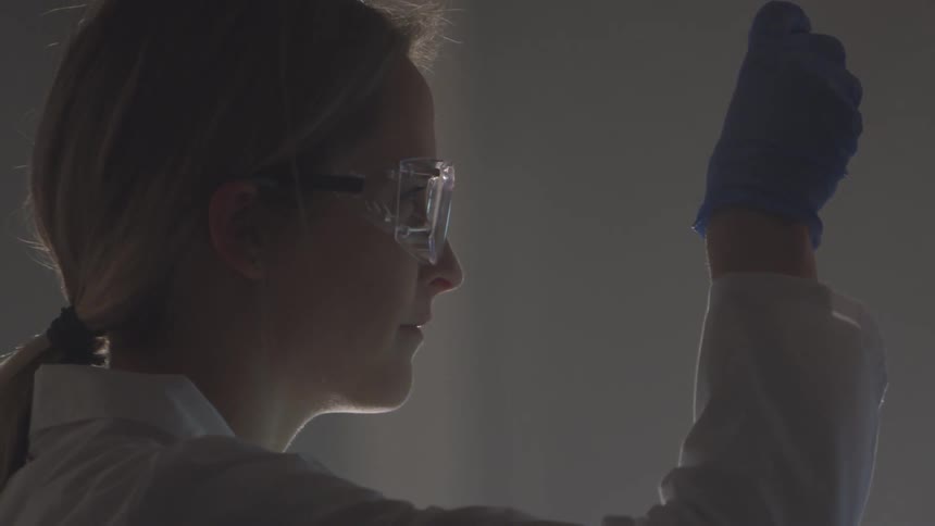 A female lab technician holding a tube of blue liquid