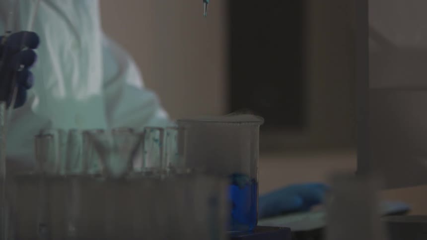Person lifting fluid out of a beaker