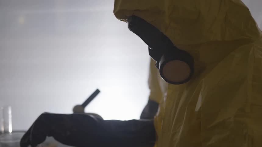 Two people in hazmat suits working