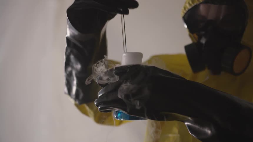 A person wearing a hazmat suit stirring chemicals