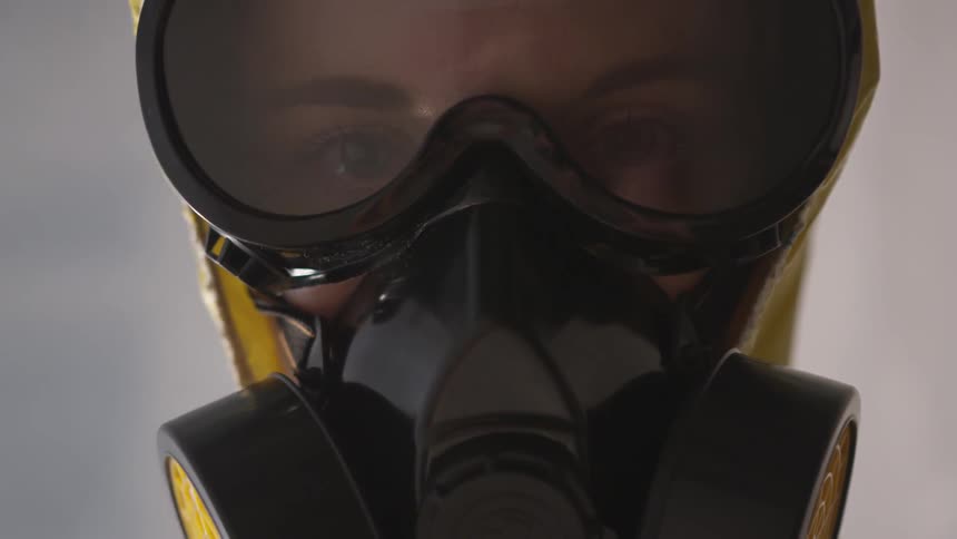 A woman wearing a gas mask in a yellow hazmat suit
