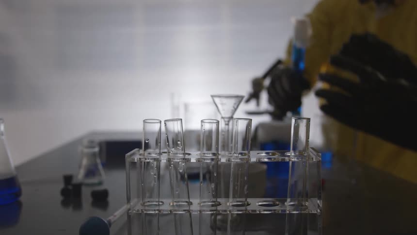 A person taking the cap off of a test tube full of blue liquid