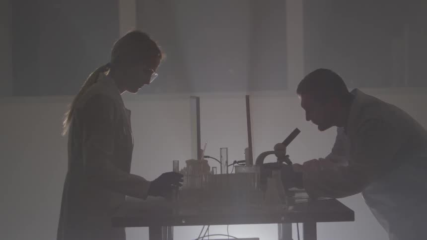 Two scientists work in a dark lab room