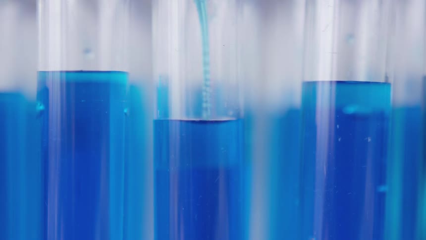 A test tube being filled with blue liquid