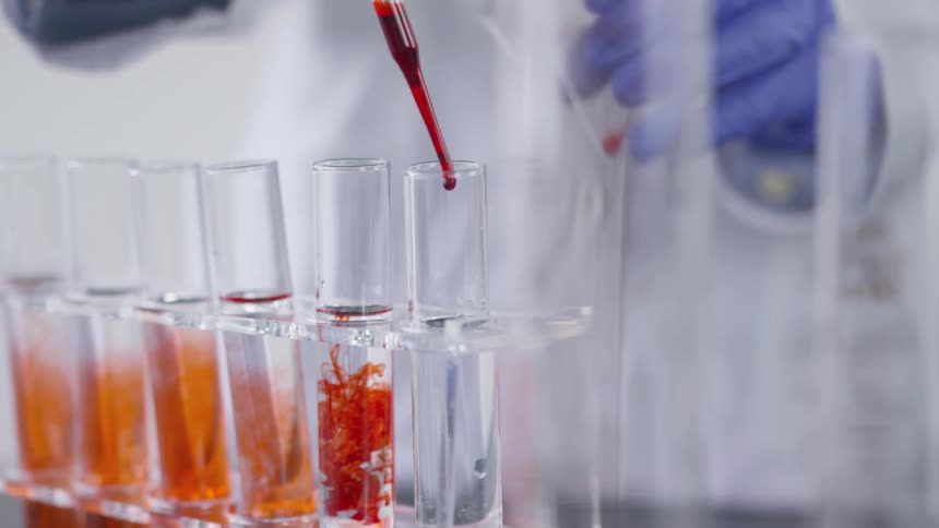 A lab technician mixing liquids in vials with a dropper
