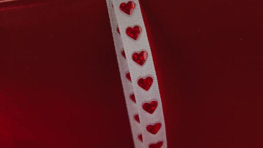 White band with a series of red hearts embedded into the band