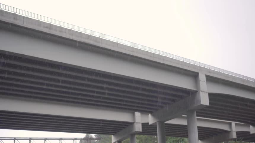 Rain falls while the camera looks at an overpass bridge