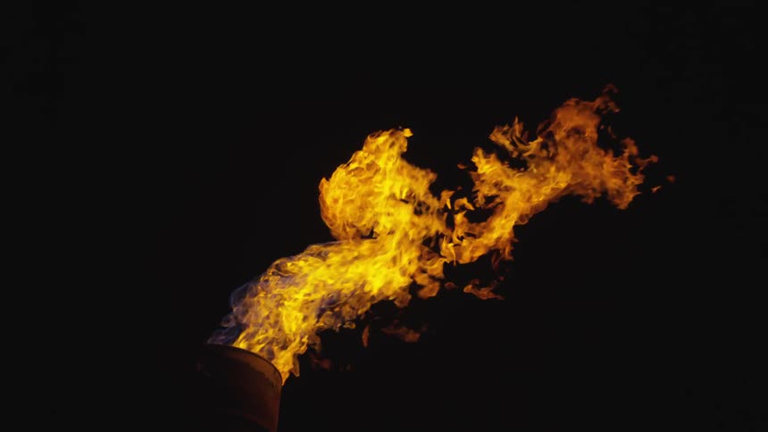 A barrel at nighttime with fire coming out of it