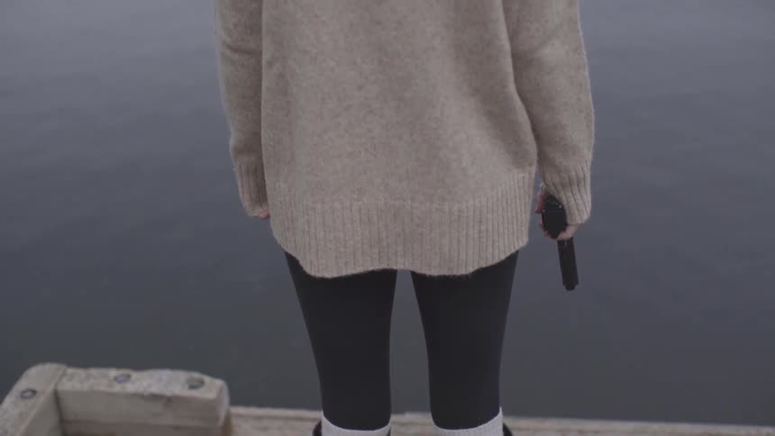 A woman is holding a gun outdoors on a dock
