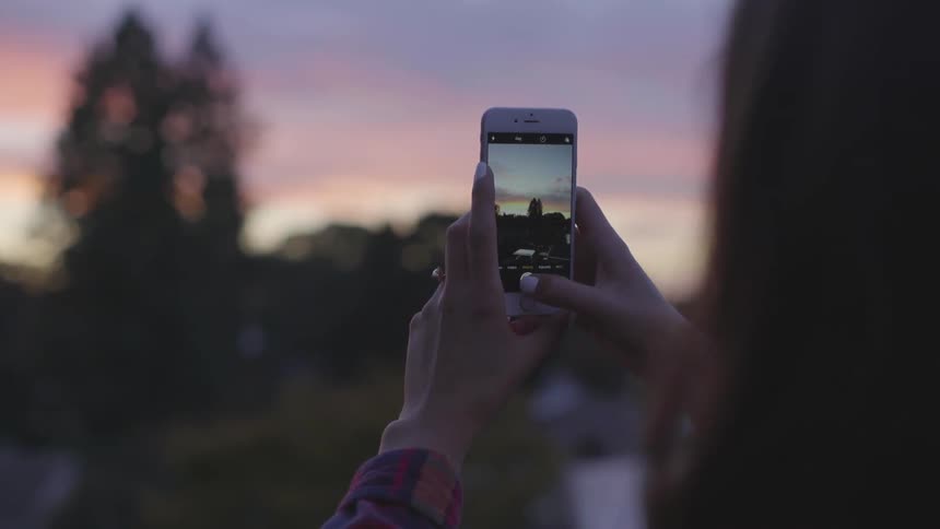 A woman takes a picture of the skyline with her smartphone