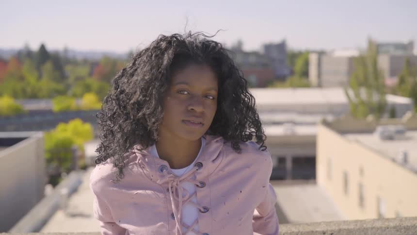 Person looks into the camera while standing on a rooftop