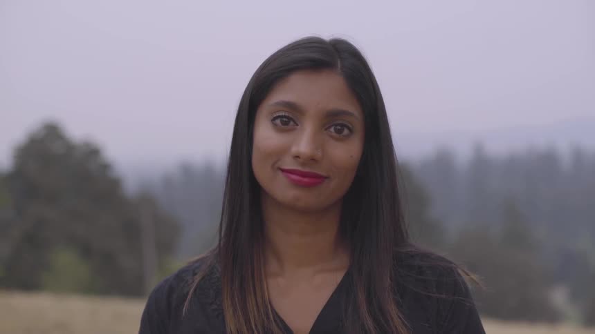 A young woman looks at the camera and smiles