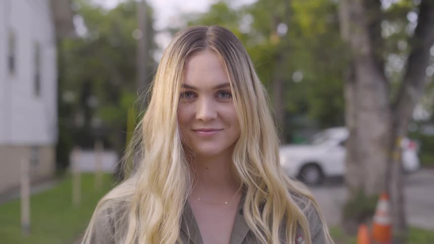 A blonde white woman steps forward and smiles