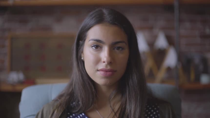 Young woman seated in chair turns to camera