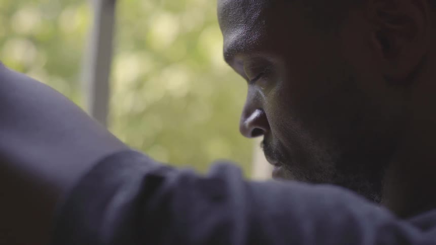 Man closes his eyes near window