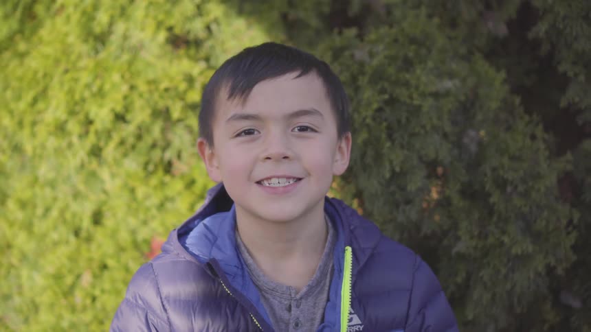 A child is outdoors smiling