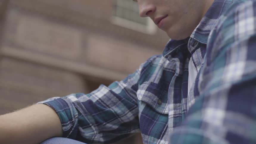 A man sits and looks towards his lap