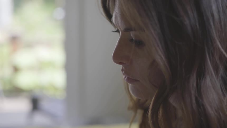 A woman looks downward in a house