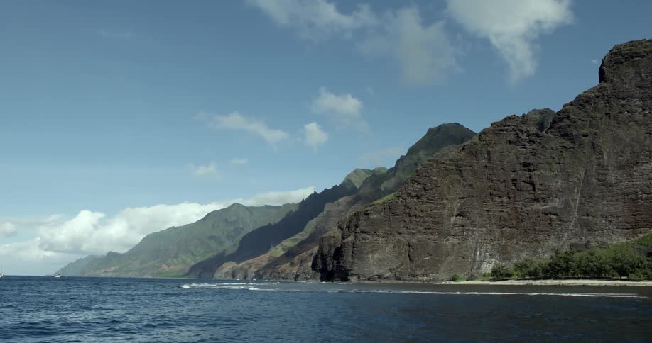 A range of mountains next to a beach as seen from a boat