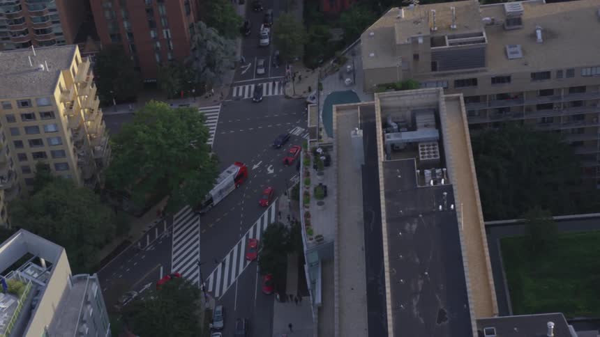 A city filled with condominiums has several intersecting roads passing between with cars buses and people going up and down it
