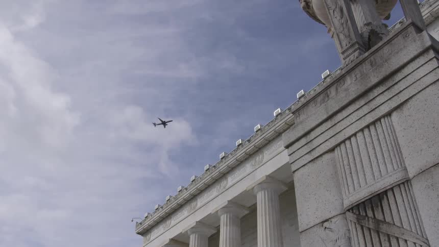 A plane flies over a large building
