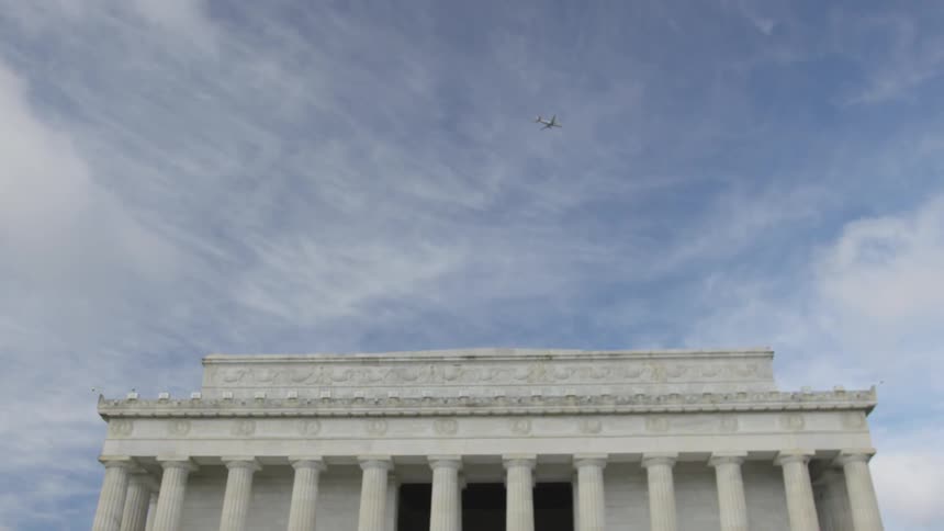 An airplane flies over the monument