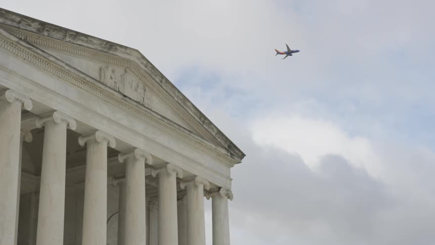 Plane flying over a courthouse on a cloudy day