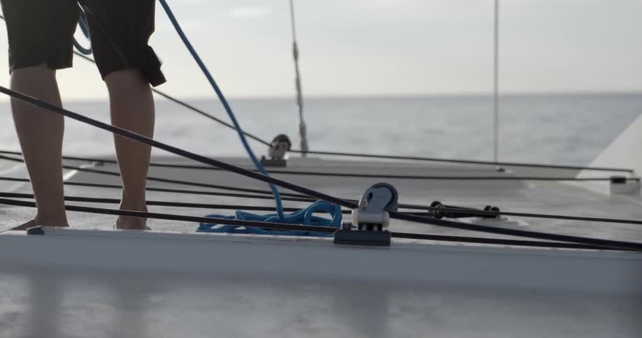 A person winding up rope on the deck of a boat
