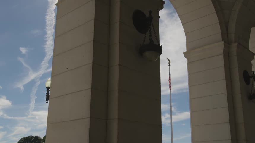 A flag on top of a pole can be seen through an arch