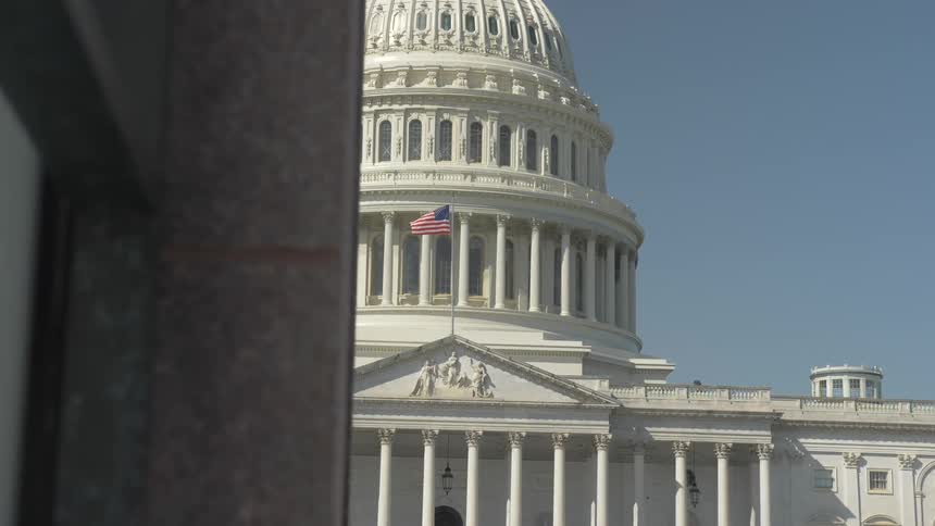 The united states capitol with the us flag waving in the front
