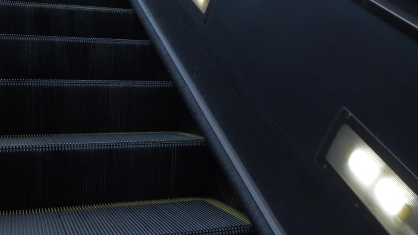 An escalator moves up as lights glide by on the side