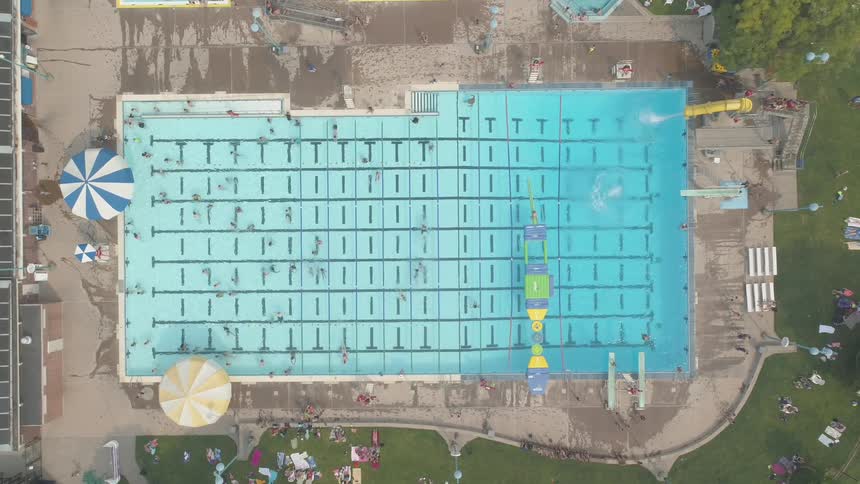 An olympic size swimming pool with slides and umbrellas