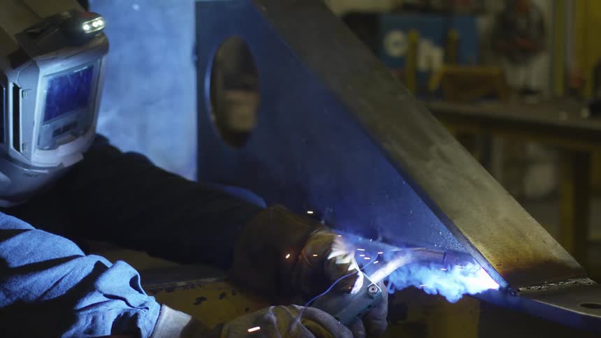 A worker welds metal with a torch