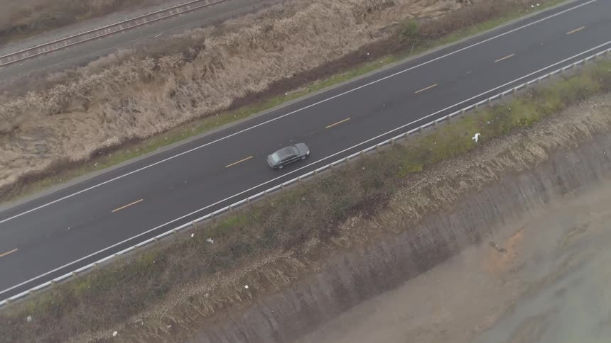 Black cars drives on the road next to railway in the daytime