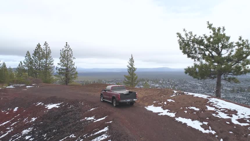 Pickup truck on a dirt road drives on a hill to the left