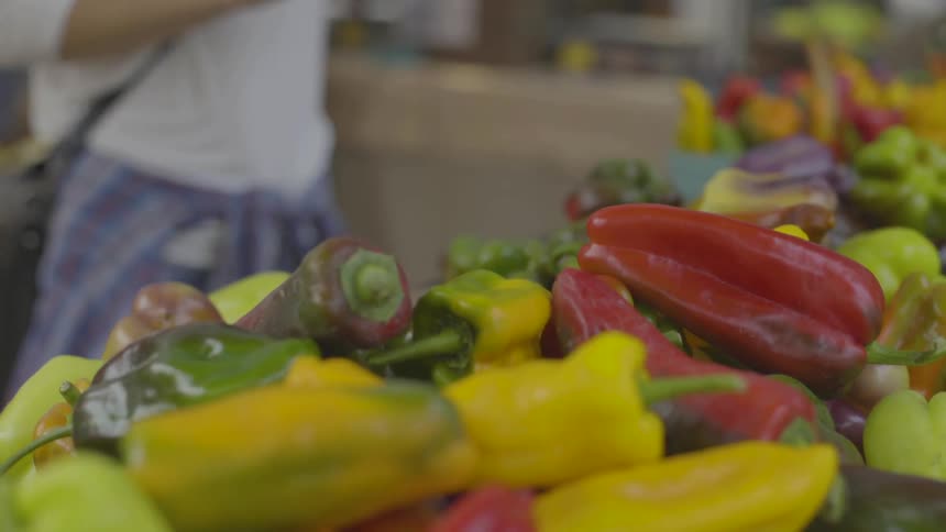 A white woman looks over the vegetables at a farmers market