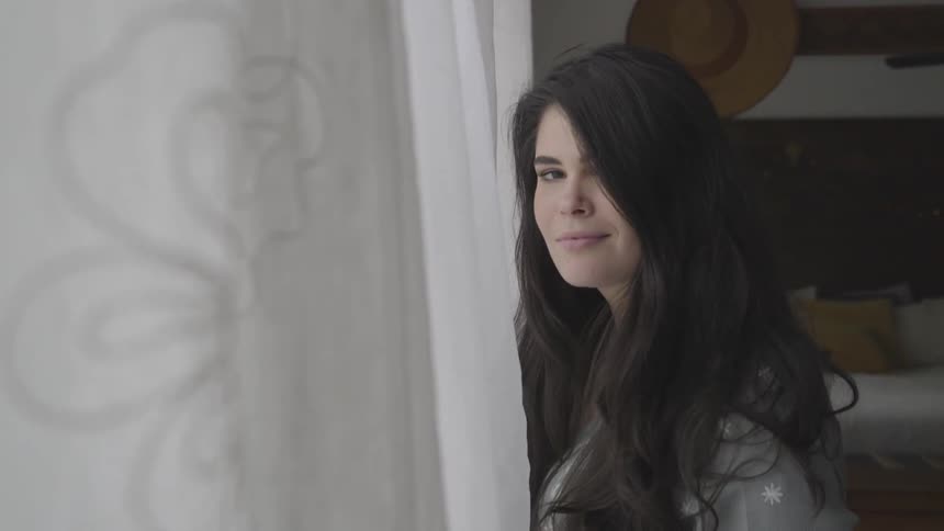 A woman standing by curtains