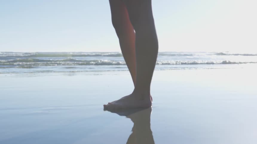 Woman's legs standing on the beach