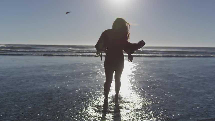 A woman walking into the sea on a sunny day