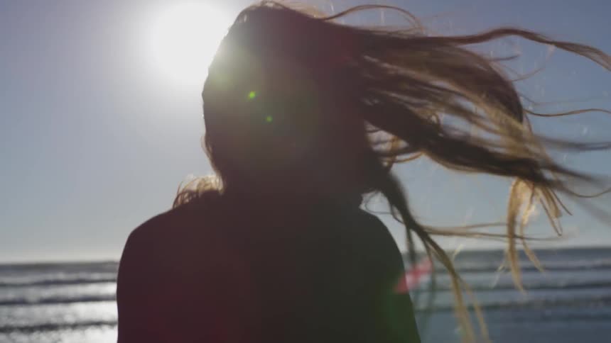 Woman runs towards the ocean under the bright sun