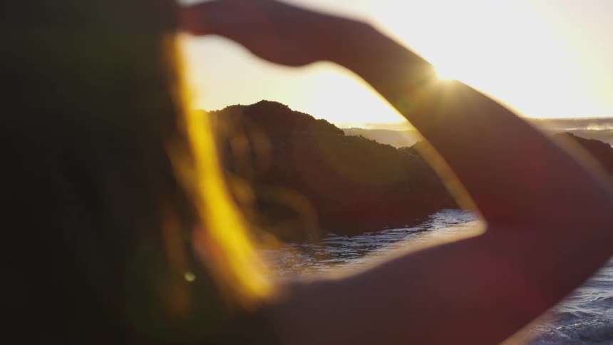 A woman blocking the sun as she looks to the ocean