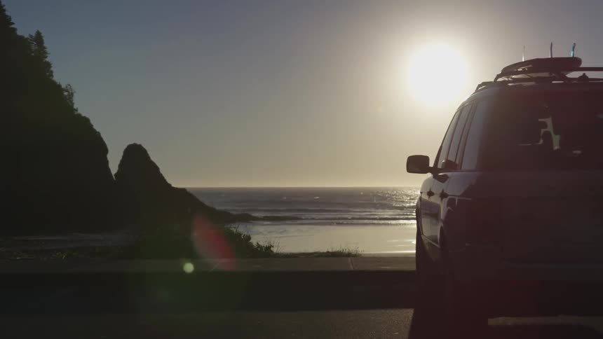Camera looks at a car parked looking over the beach
