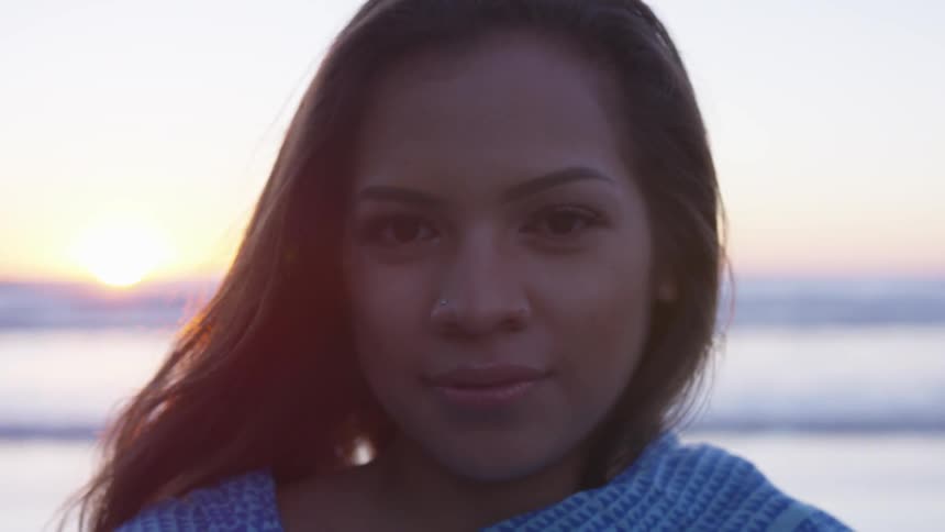 A woman poses on the beach at sunset