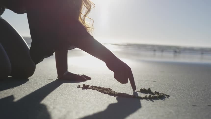 A person is drawing in the sand