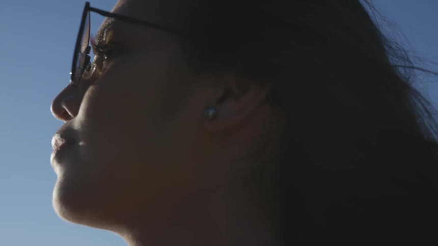 Woman wearing glasses looks out at clear blue sky